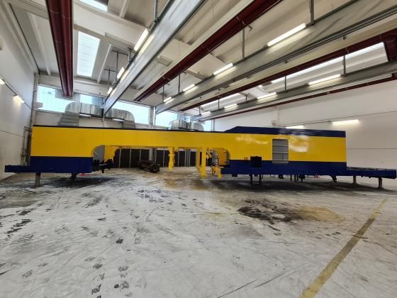 Macchina industriale gialla e blu all'interno di un grande magazzino.
