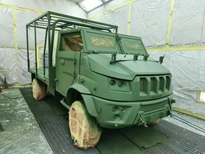 Veicolo militare verde in una cabina di verniciatura, ricoperto di vernice verde.