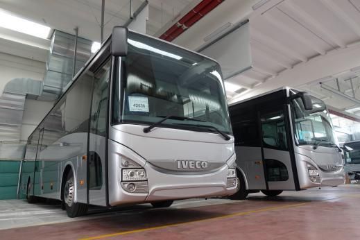 Due autobus Iveco color argento parcheggiati all'interno di un magazzino.