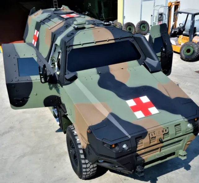 Ambulanza militare mimetizzata con porte aperte e croci rosse.