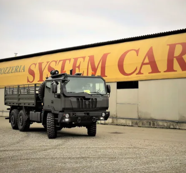 Un camion militare verde scuro parcheggiato davanti alla sede System Car