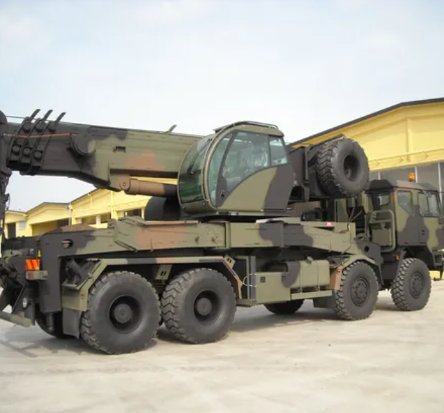 Un camion con gru in stile militare, in mimetica, parcheggiato all'aperto in una giornata limpida.