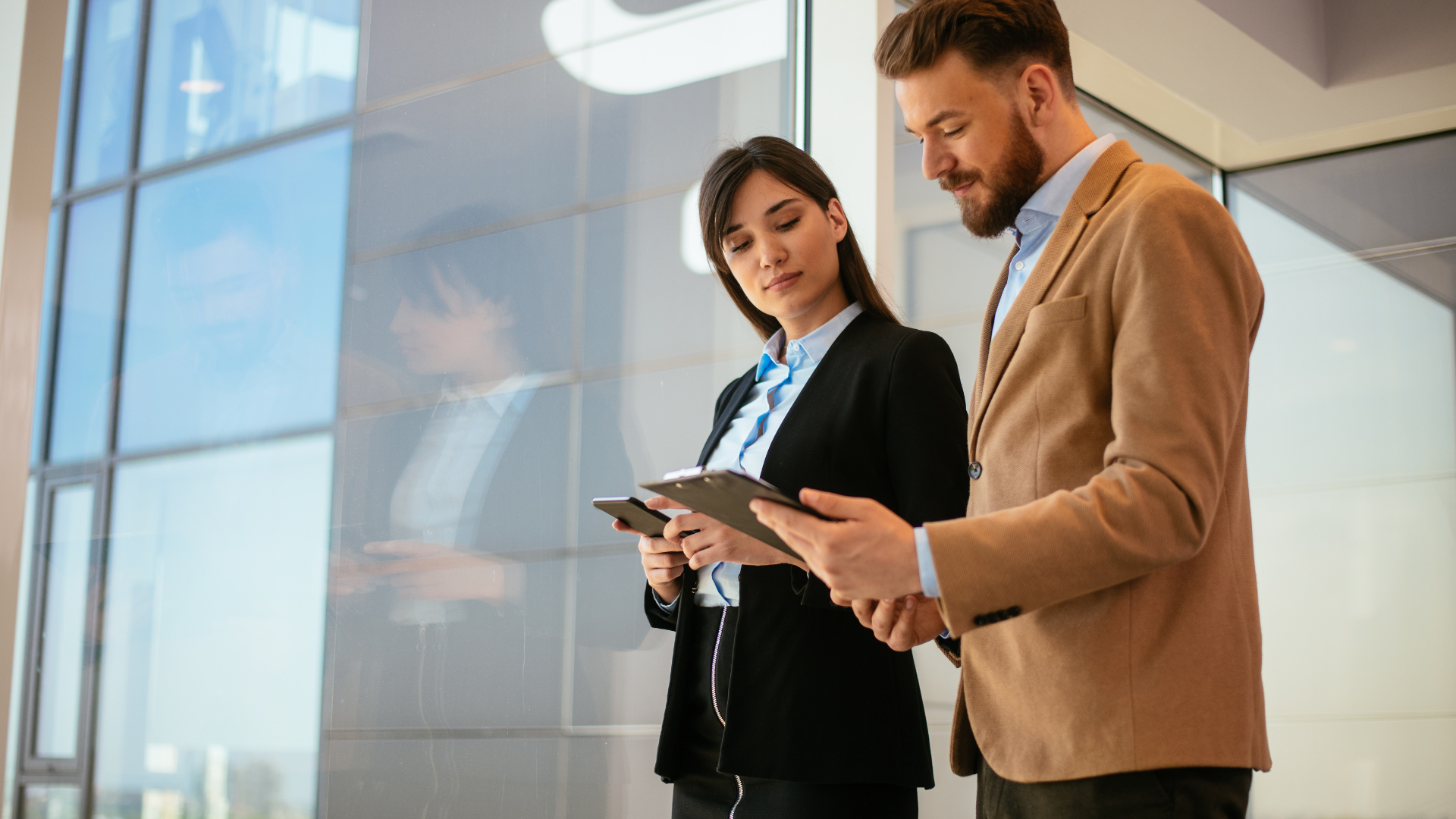 Woman and man in business attire reviewing documents, indoors.