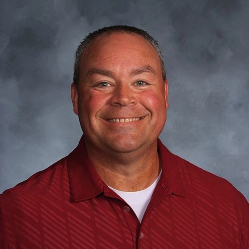 A man in a red shirt is smiling for the camera.