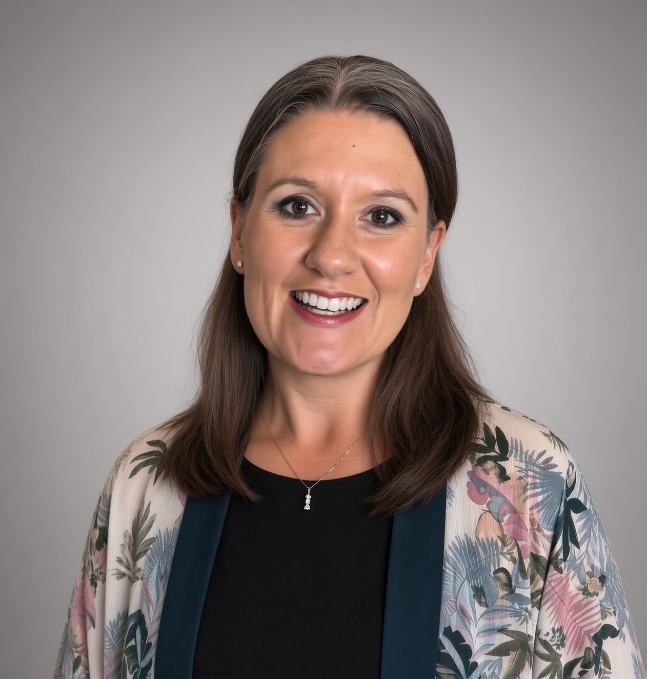 A woman in a red plaid shirt is smiling in front of a brick wall.