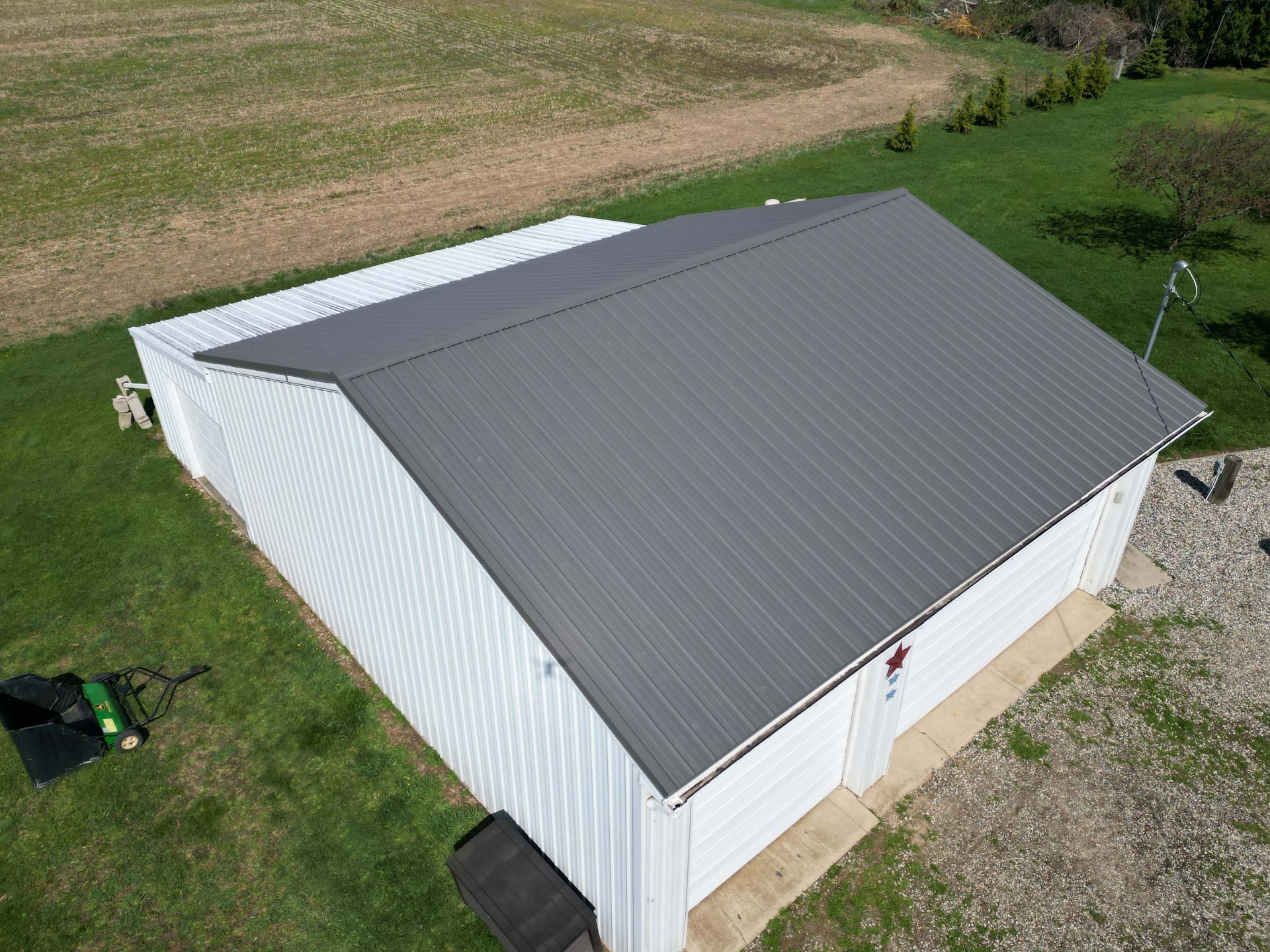 White barn with gray metal roof in a grassy field.