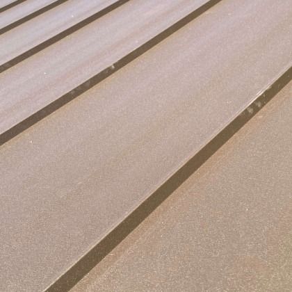 Close-up of tan metal roof panels with shadows.
