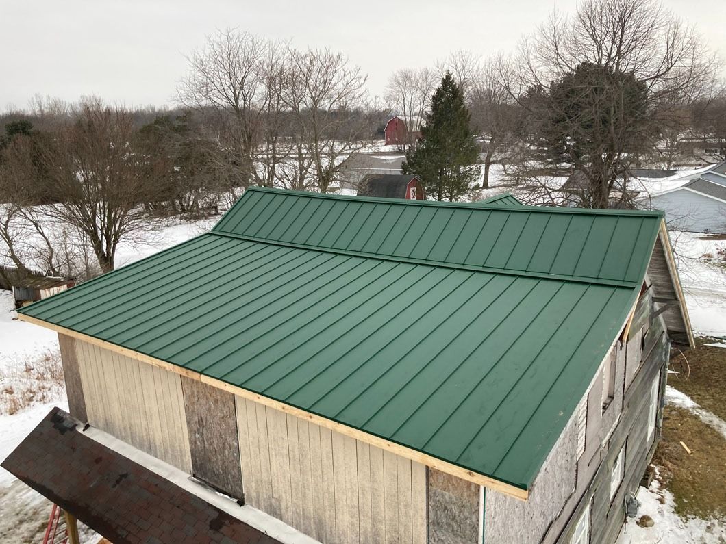 Green metal roof on a weathered wooden building, snowy outdoor setting.