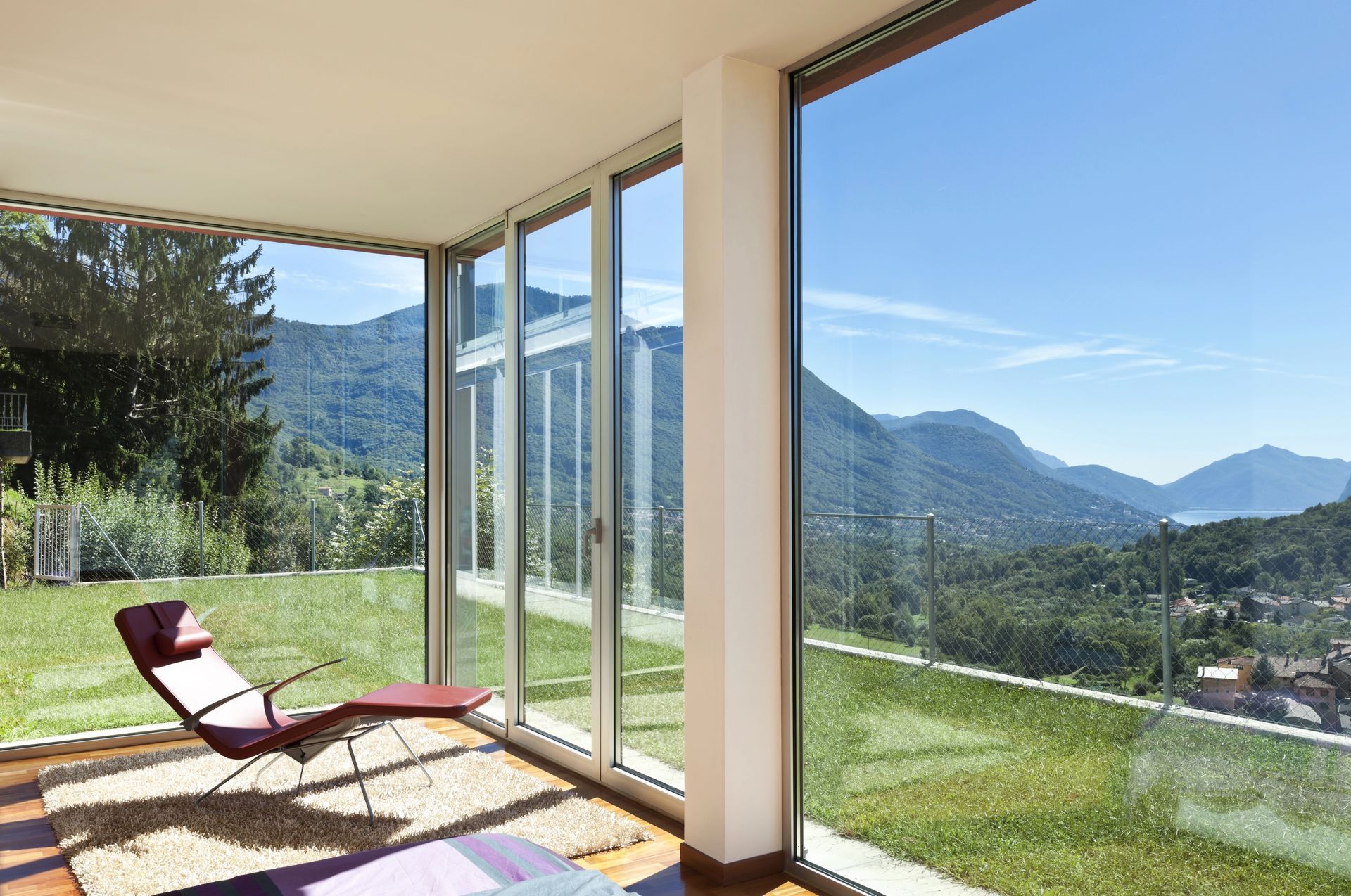 Camera moderna con pareti bianche, porta aperta e poltrona a uovo scura su pavimento in legno.