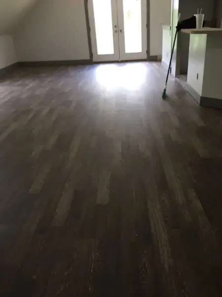 Dark hardwood floor in a room with white doors and a partially visible white counter.