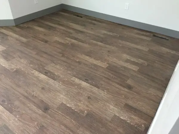 Wooden floor in a room, with grey baseboards.