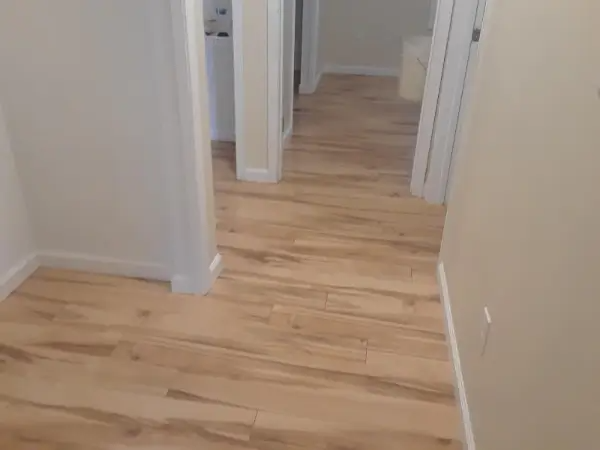 Hallway with light wood-look flooring, cream walls, and white door frames leading to other rooms.