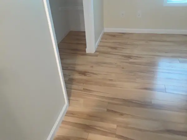 Light wood-look flooring in a room with light-colored walls. An open doorway leads to another space.