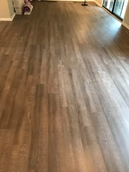 Wood-look laminate flooring in a room with natural light and a white wall.