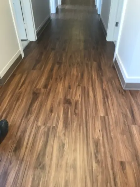 Hallway with dark wood-look flooring. White walls, doors, and trim.