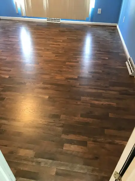 Dark brown wood flooring in a room with blue walls and a window reflecting light.