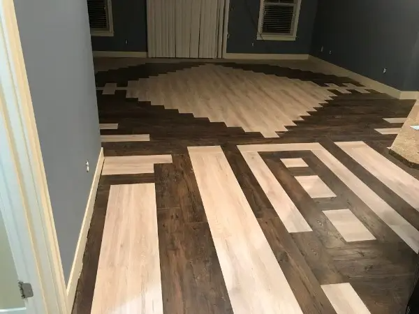 Wooden floor with light and dark planks arranged in geometric patterns.