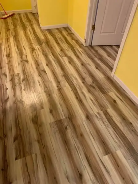 Wooden-look laminate flooring in room with yellow walls and a white door.