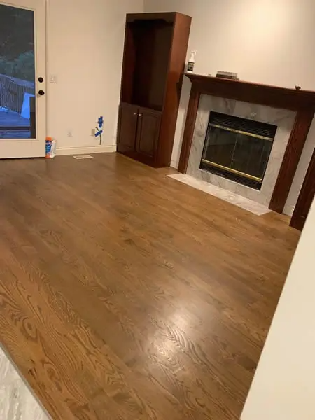 Newly installed hardwood floor in a room with a fireplace and built-in cabinet.