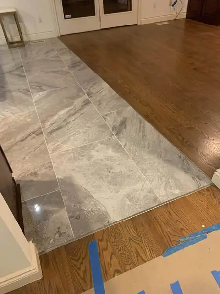 Floor transition: gray tile meets brown hardwood with a metal strip.