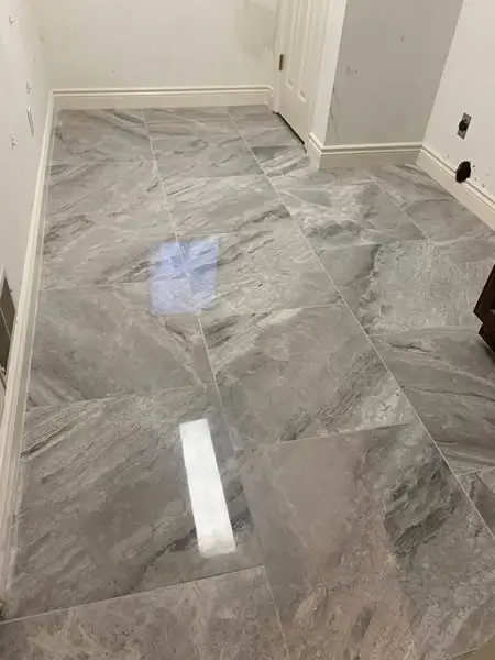 Gray tiled floor in a room, white trim along walls and baseboards.