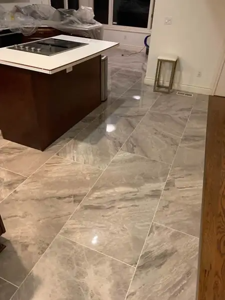 Kitchen with marble-like floor tiles, dark brown island with cooktop, and natural light.