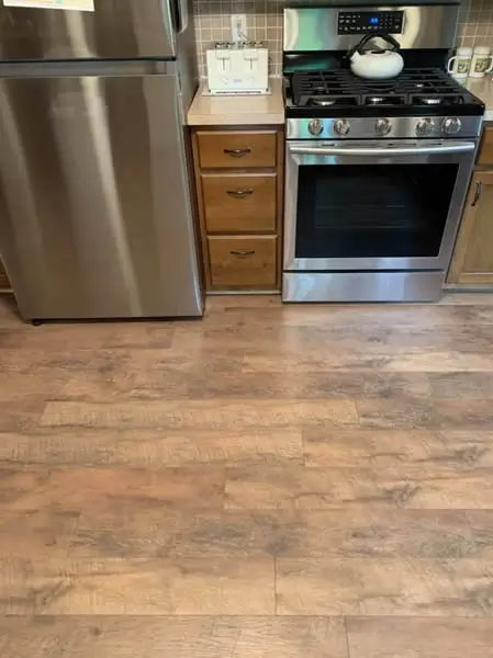 Kitchen with stainless steel appliances, wood cabinets, and wood-look flooring.