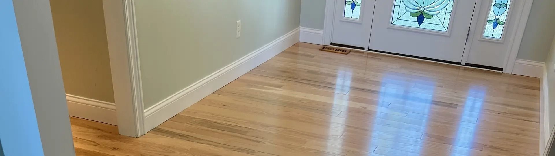 Hardwood floor with a white door and trim. Pale green wall.