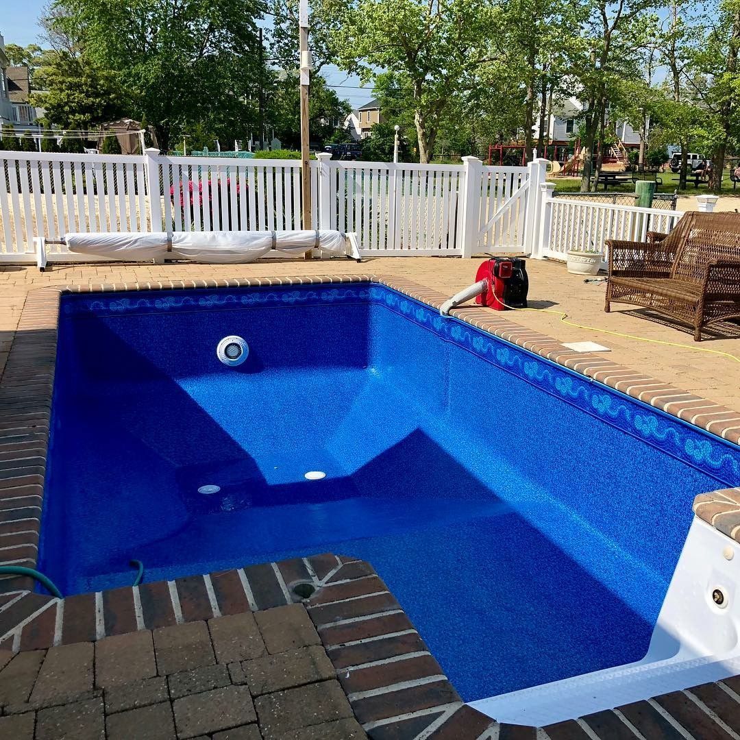 A large blue swimming pool is sitting on top of a brick patio.