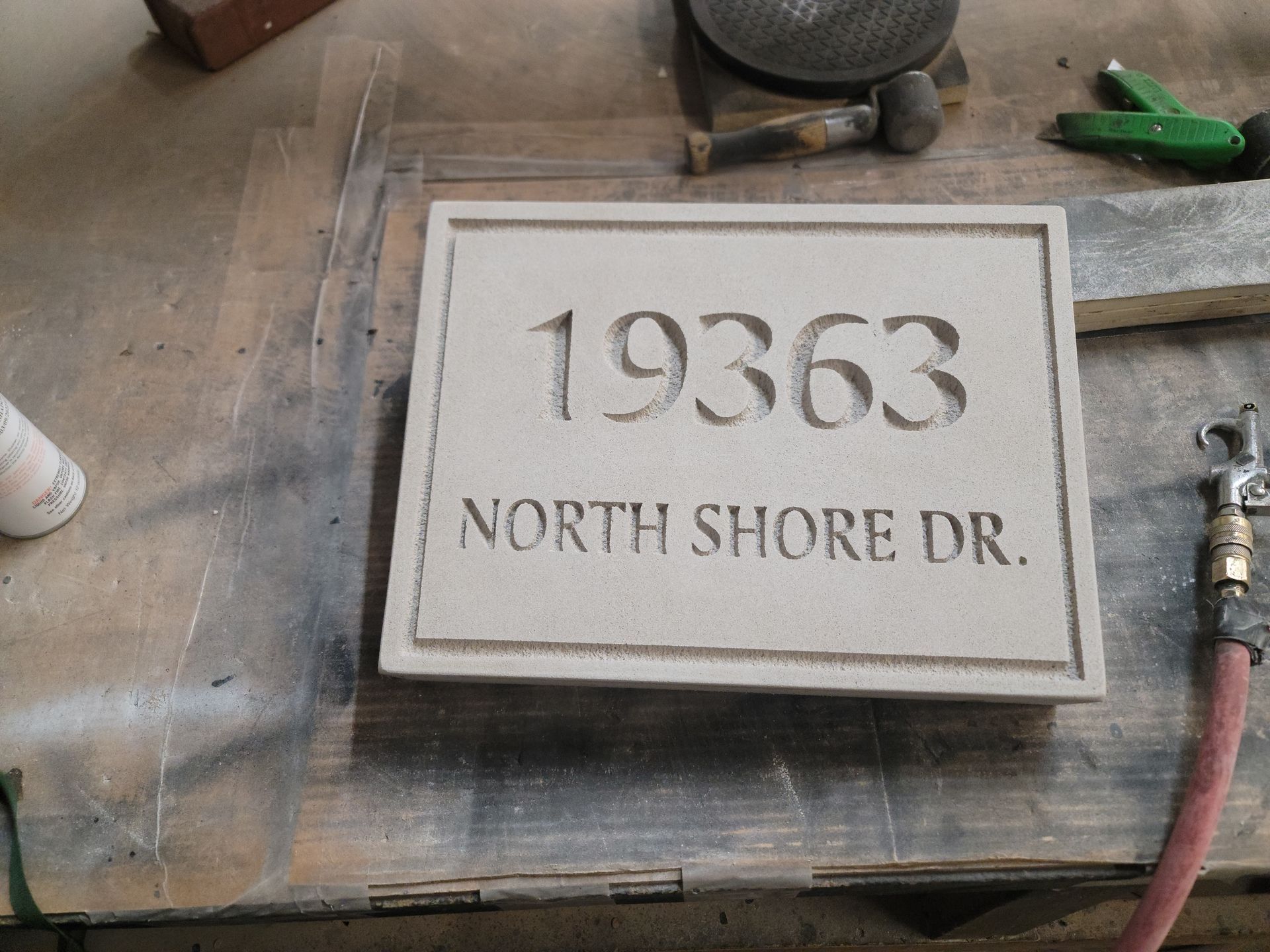 Sandstone address marker carved with numbers and street name, on a workbench.