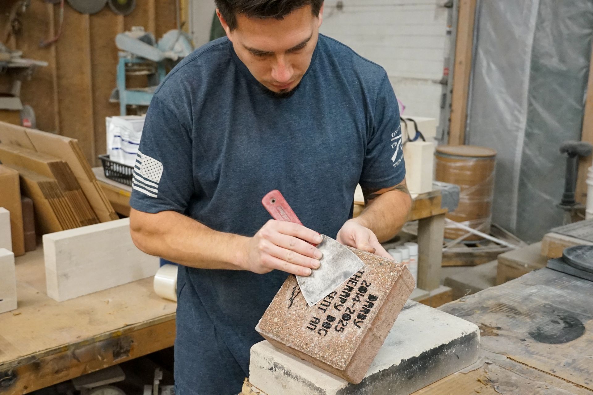 Man using a tool to smooth the surface of a brick in a workshop.