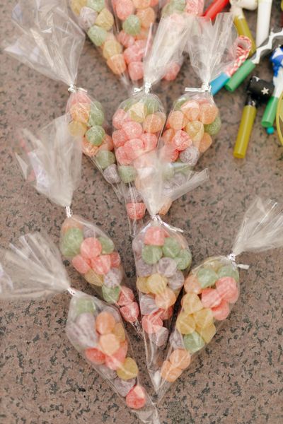 Clear bags of colorful pastel candies tied to a branch on a speckled countertop.