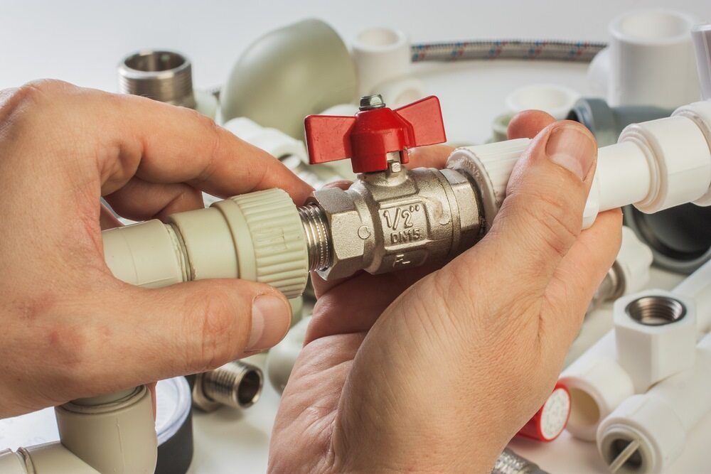 Hands Assembling Plumbing Parts — Cliff Tucker Plumbing In Emerald, QLD