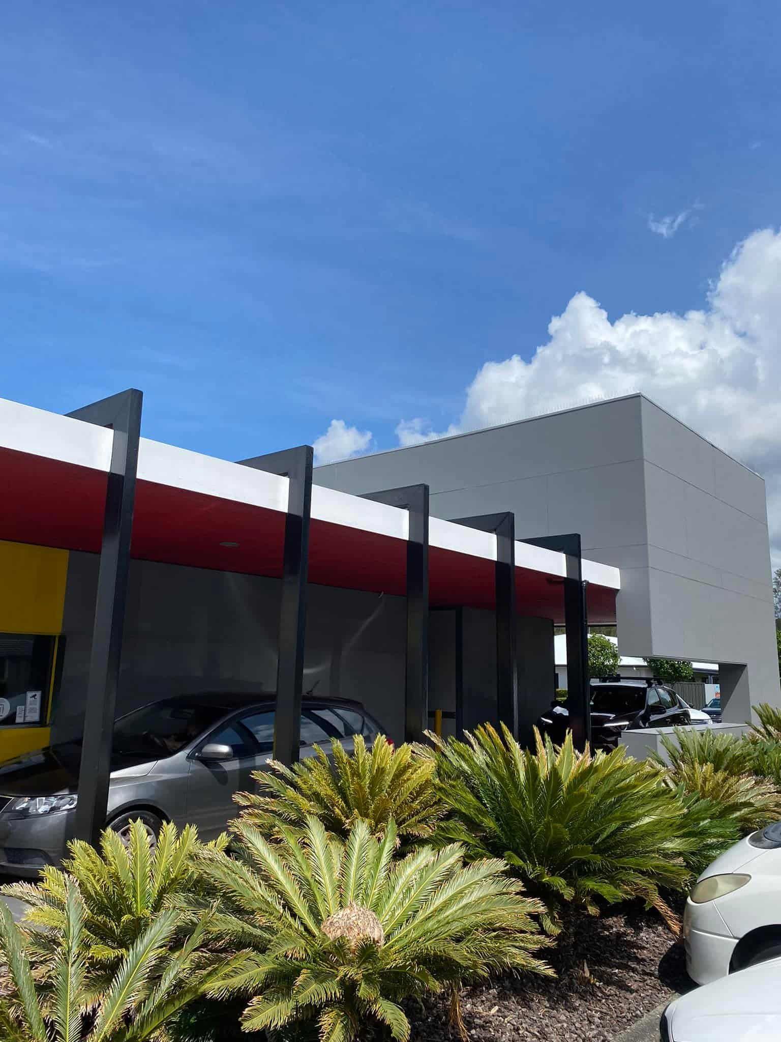 Drive-Thru of a Fast Food Restaurant With Red and White Awning, Cars, and Plants — S D Maintenance In Gosford, NSW