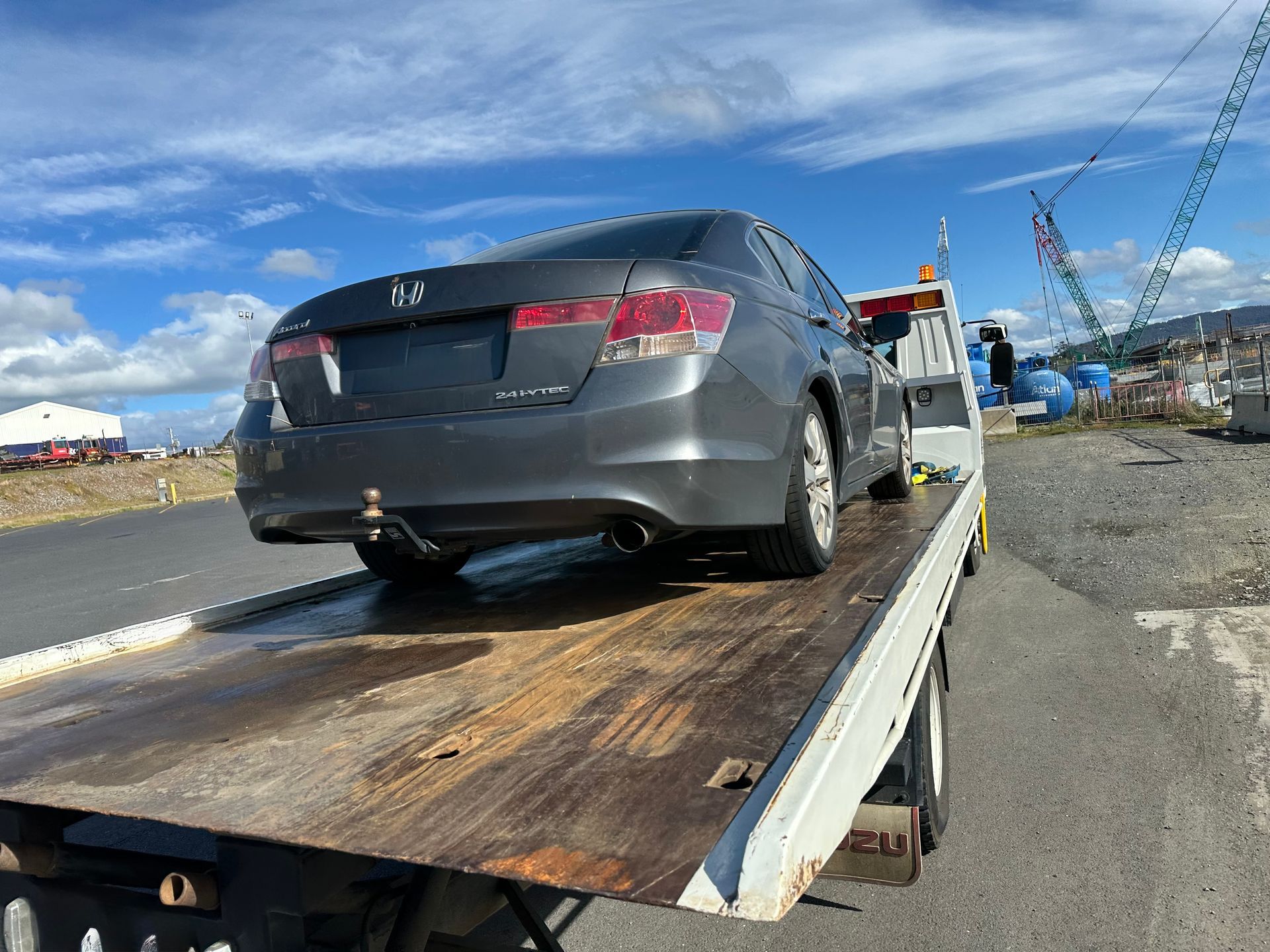 Grey Sedan on A Tow Truck Ramp Beside a Roadway Under a Blue Sky — Connect Trailers and Towing Pty Ltd In Prospect Vale, TAS 