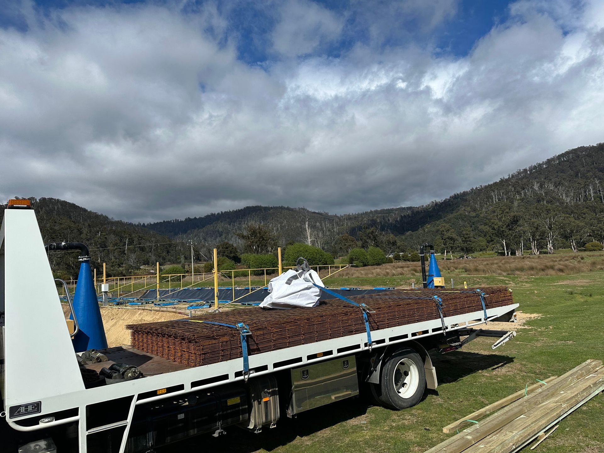 Flatbed Truck Carrying a Pile of Soil in A Grassy Field — Connect Trailers and Towing Pty Ltd In Prospect Vale, TAS 