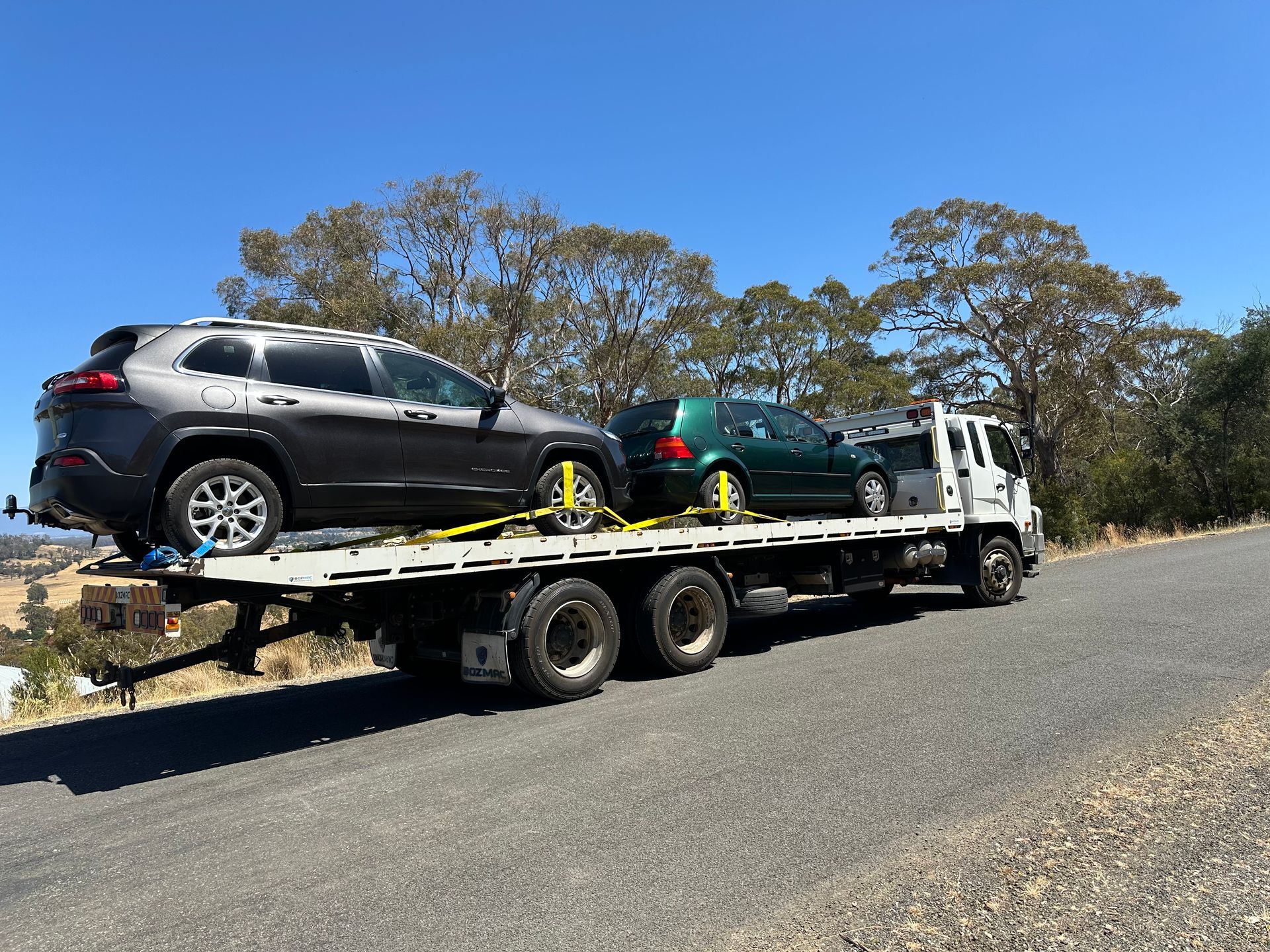 Tow Truck Hauling Two SUVs on a Flatbed Beside a Road — Connect Trailers and Towing Pty Ltd In Prospect Vale, TAS