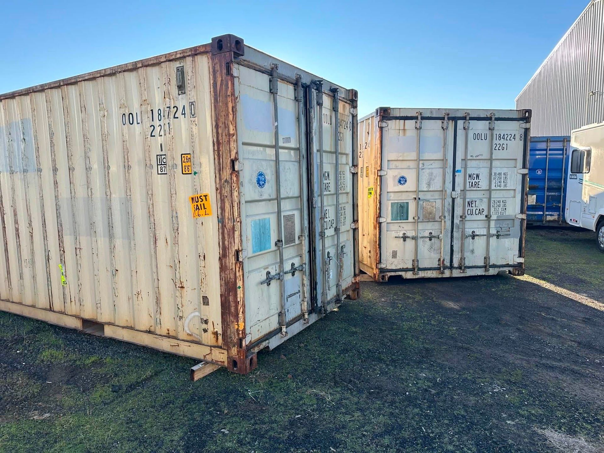 Two weathered shipping containers on gravel, one white and one light blue — Connect Trailers and Towing Pty Ltd In Prospect Vale, TAS 
