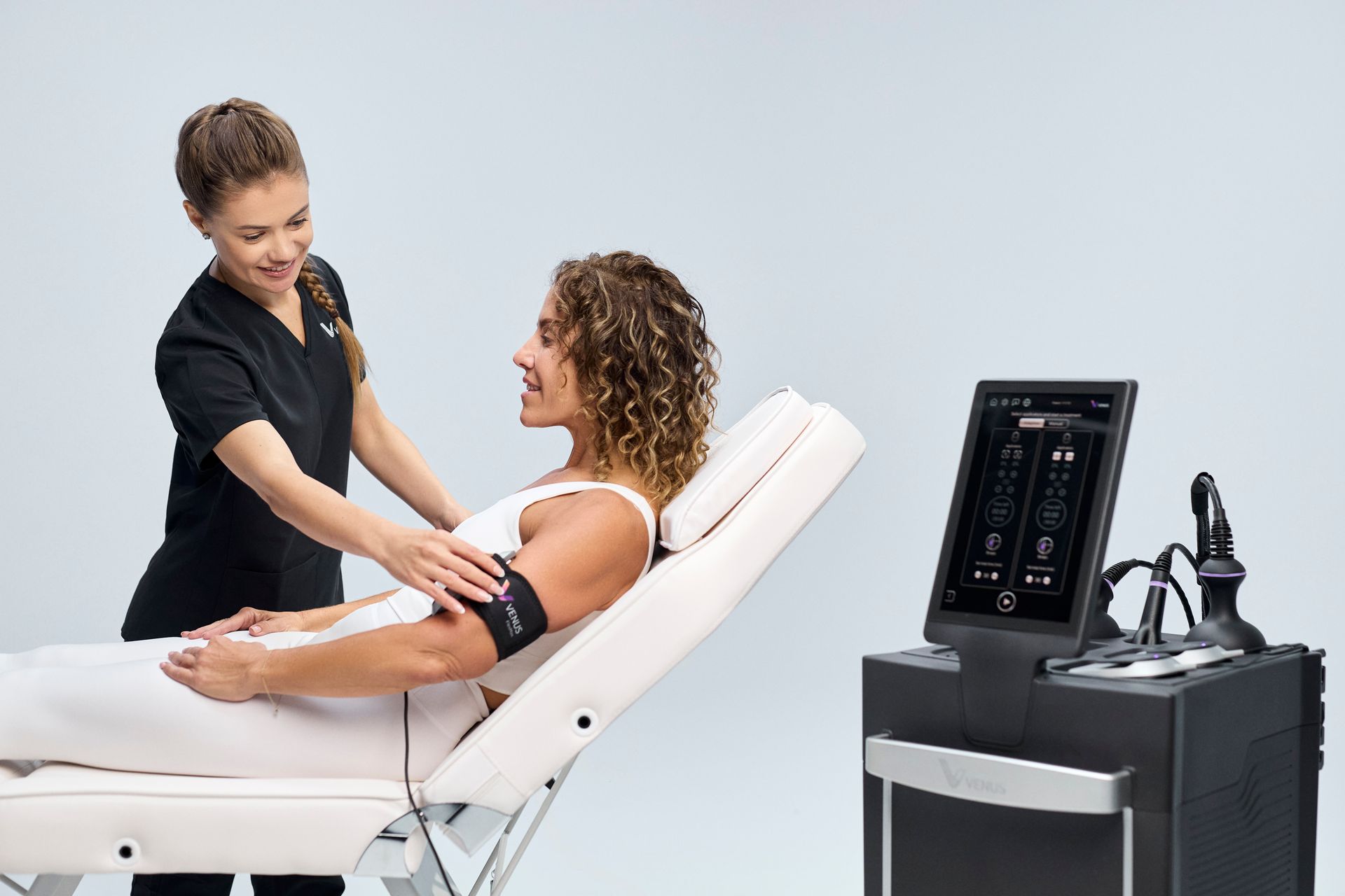 Clinician adjusting a seated patient in a treatment chair beside an ultrasound machine