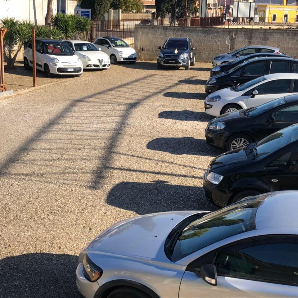 un'auto nera è parcheggiata sul lato di una strada vicino all'oceano al tramonto.