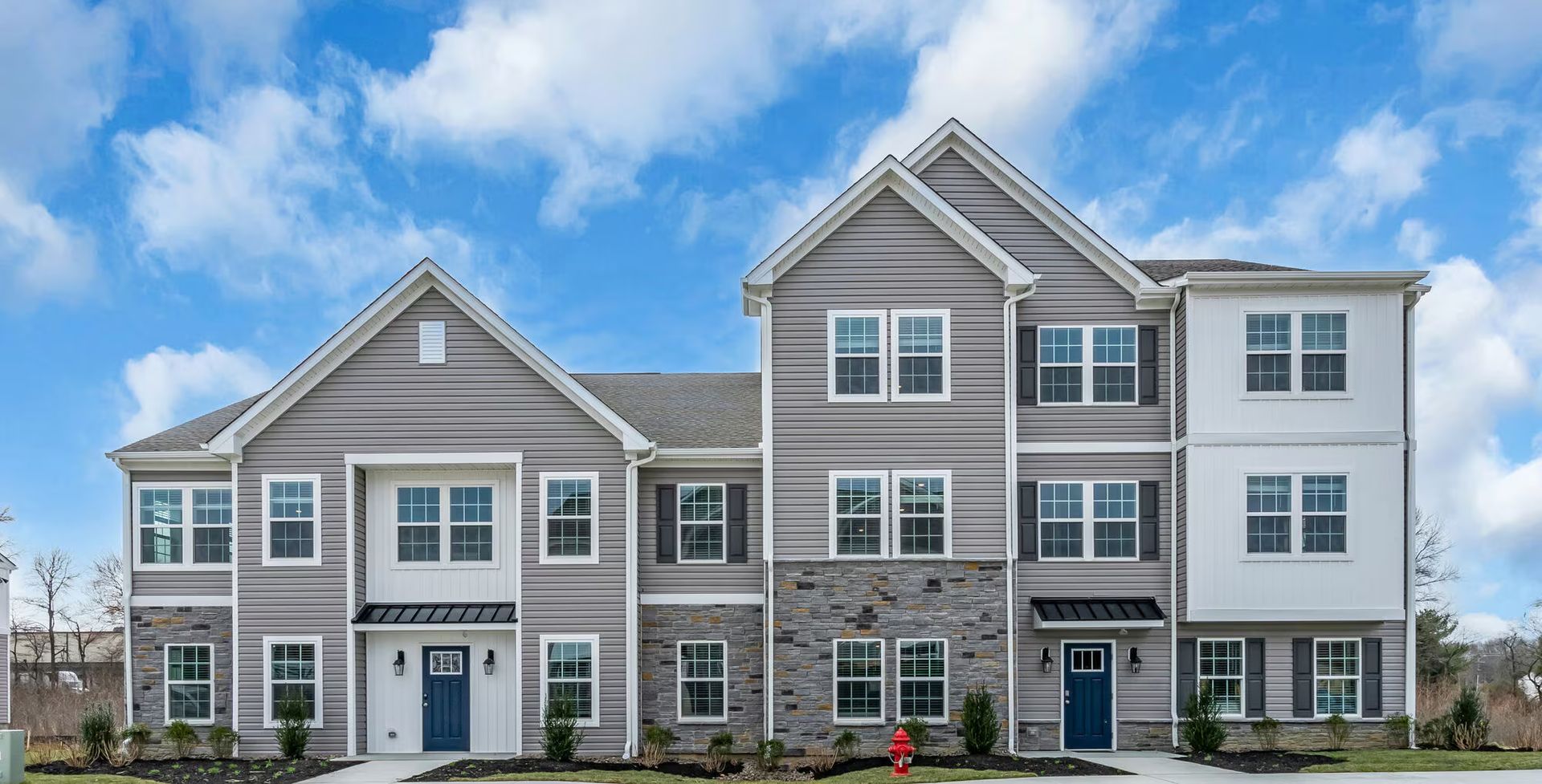 Row of modern gray-and-white townhouse apartments with front doors and dormer windows