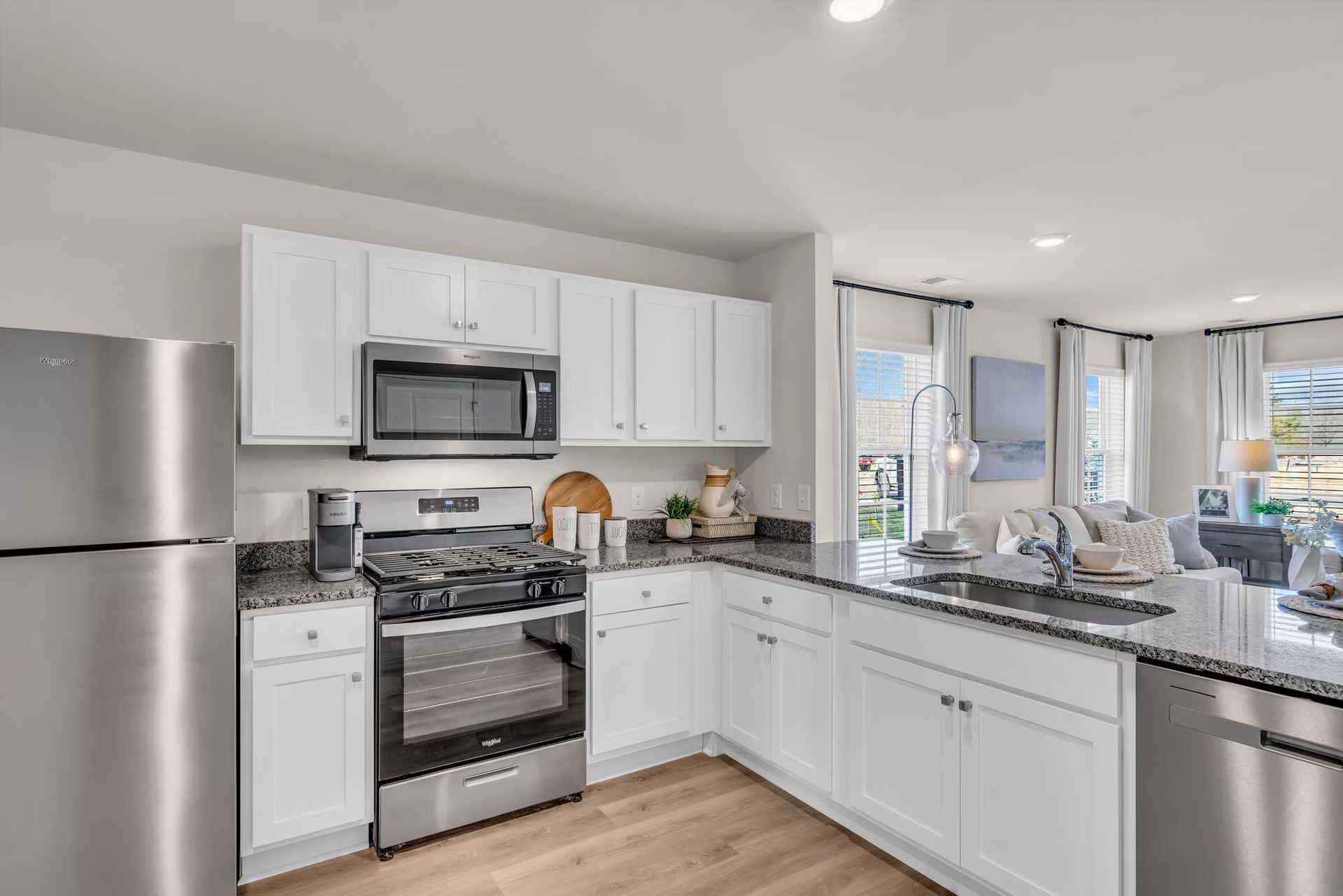 Bright modern kitchen with white cabinets, stainless appliances, and a granite countertop.