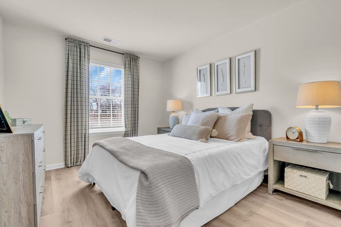 Bright bedroom with a white bed, patterned curtains, and two bedside lamps.