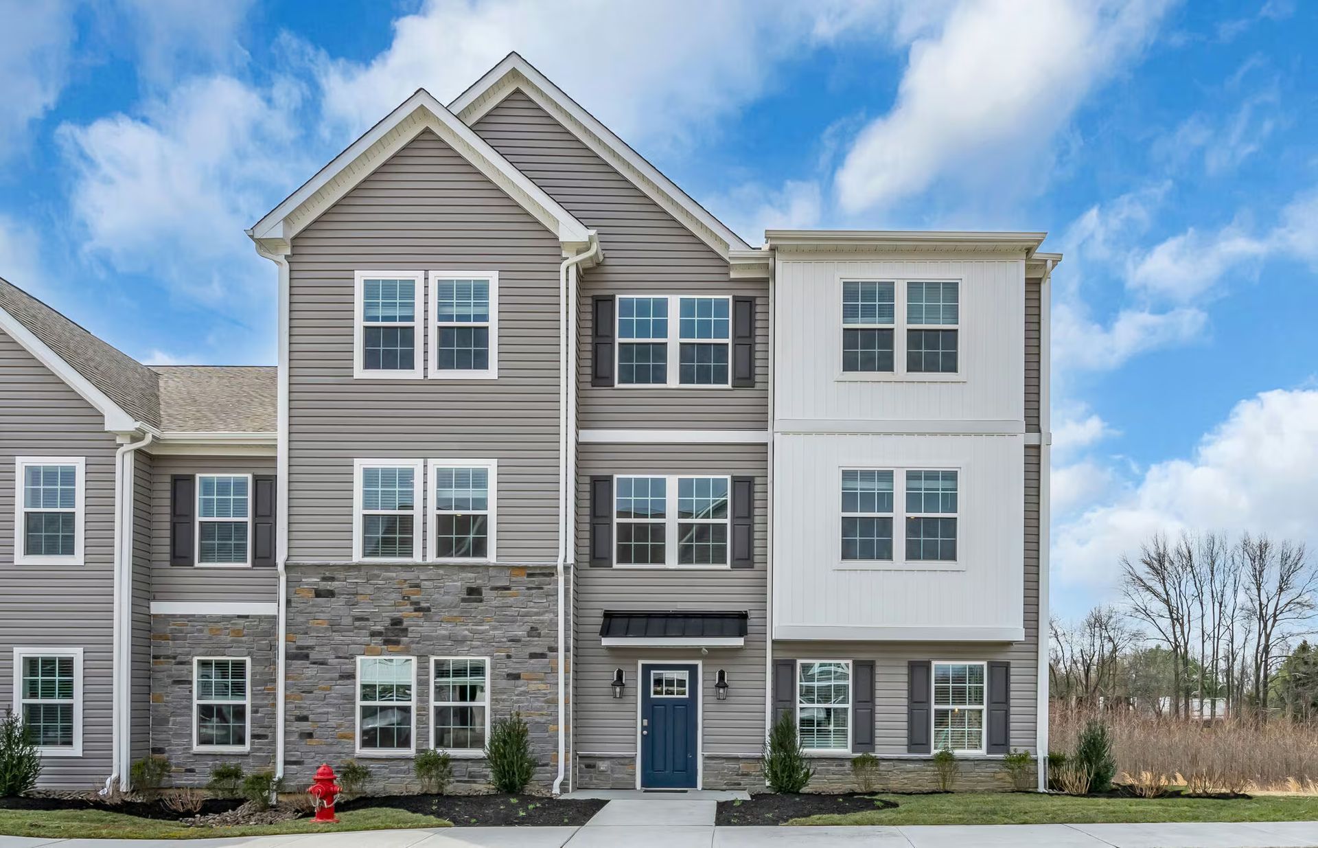 Modern gray-and-white apartment building with stone accents and a blue front door