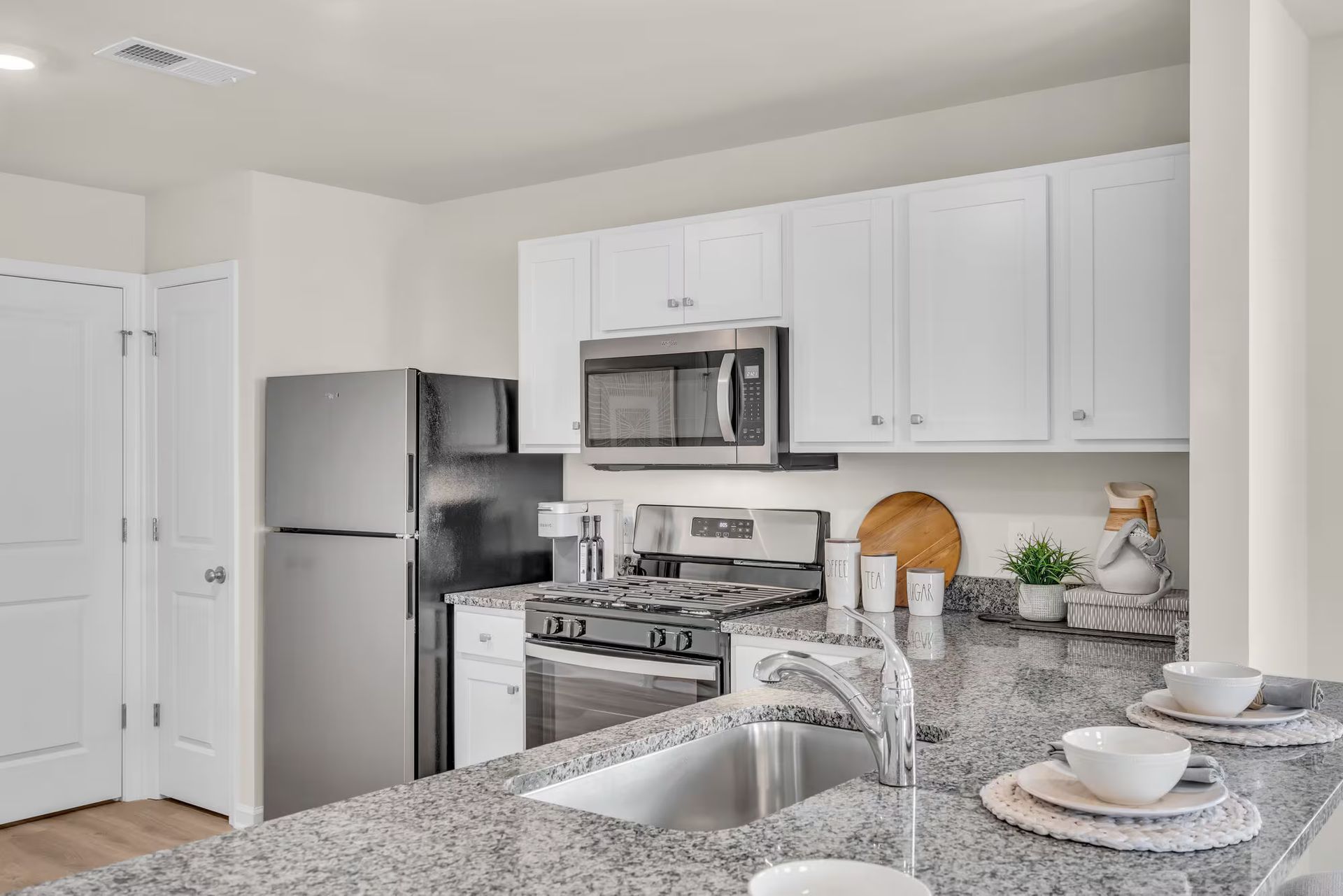 Bright modern kitchen with white cabinets, stainless appliances, and granite island counter