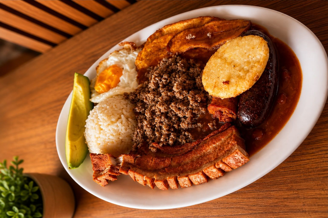 Mesa repleta de una variedad de platos para el desayuno, incluyendo arroz con frijoles, plátanos, fruta y tazones de guiso.