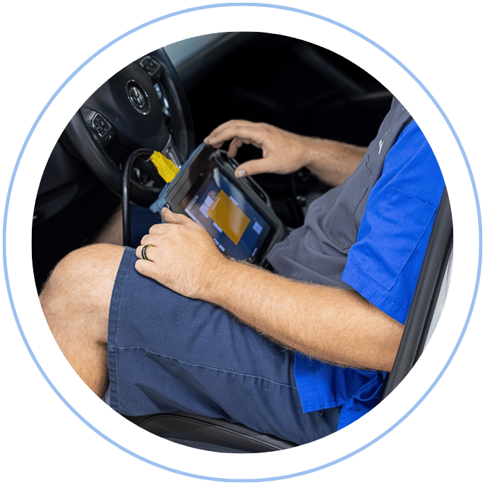 Automotive technician using a professional diagnostic scan tool connected to a vehicle to identify system faults and performance issues.