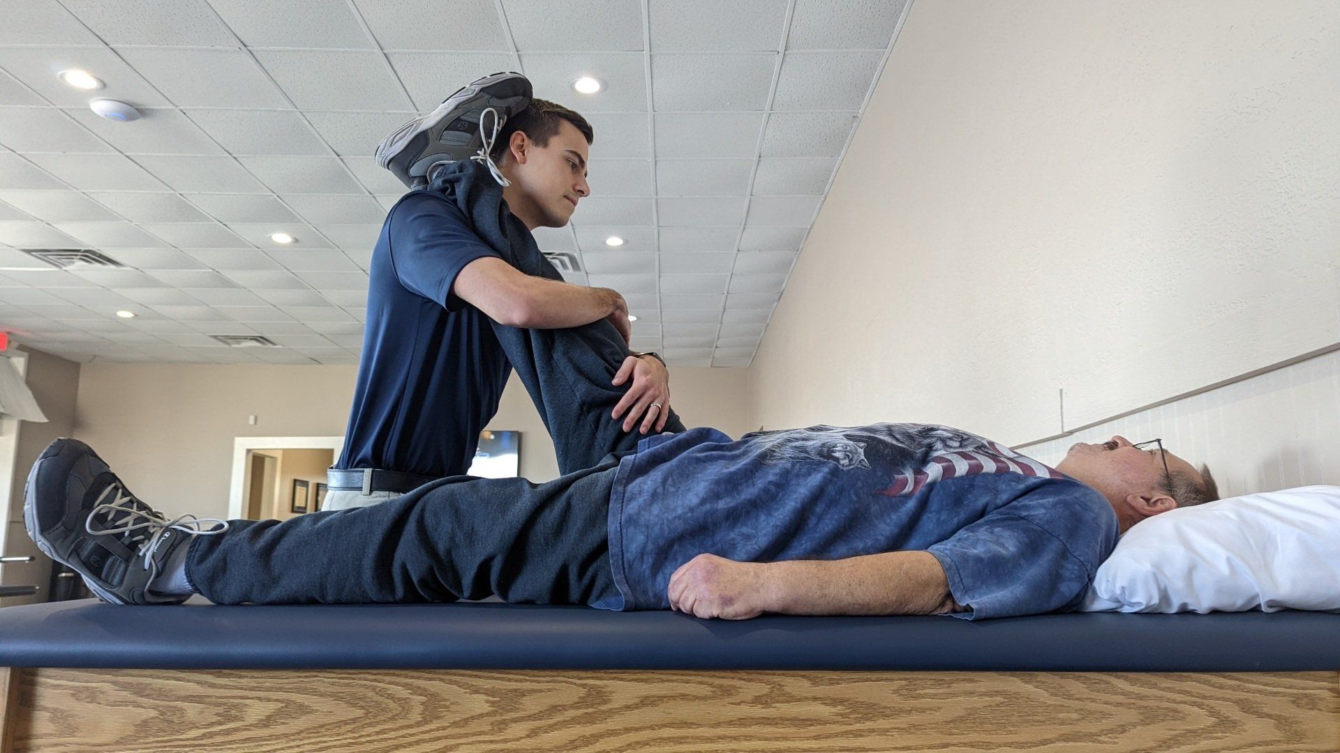 A man is laying on a table while a nurse stretches his leg.
