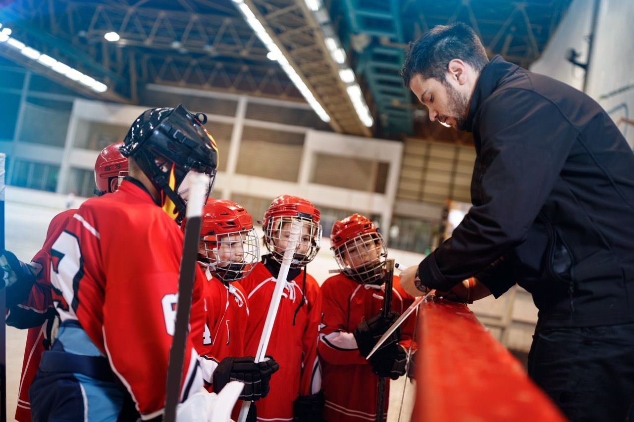 Hockey coach showing youth hockey players a drill to practice