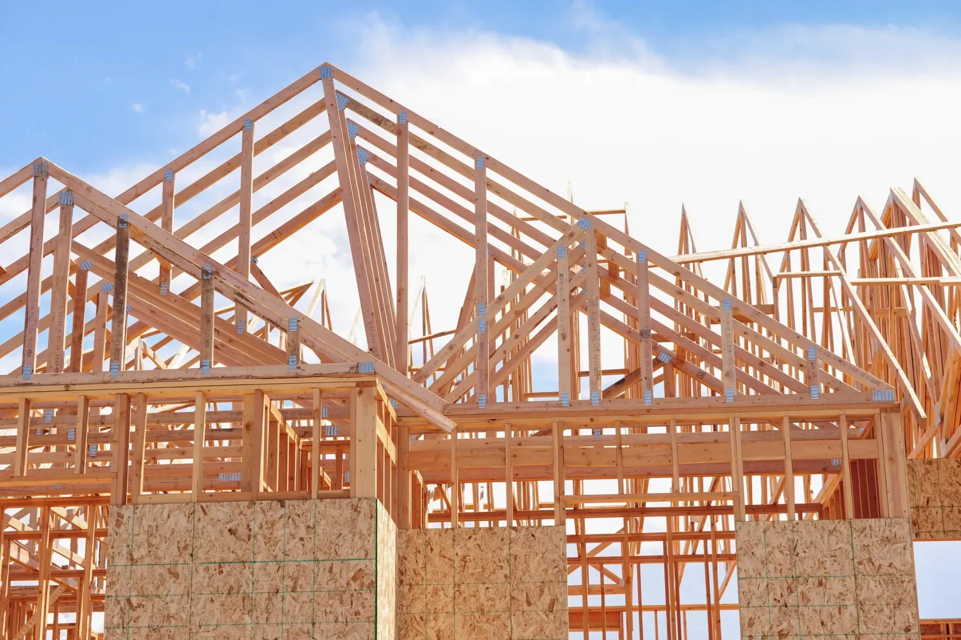 Wooden house frame under construction against a blue sky